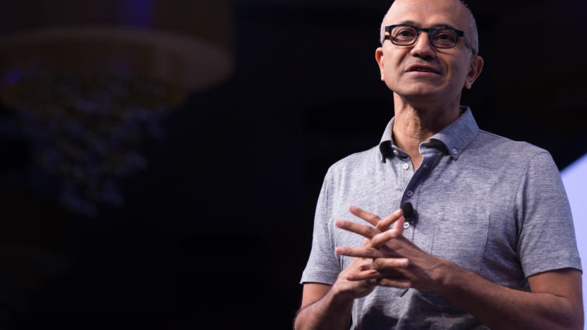 A man wearing a polo shirt and a pair of glasses with his hands clasped in front of him. 