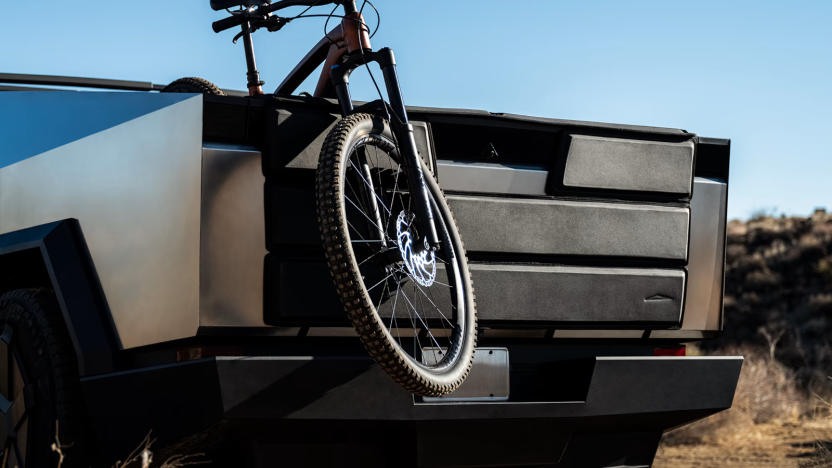 The rear end of a truck with a bike hanging out of it. 