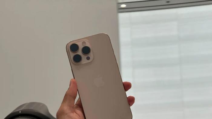 Image of the iPhone 16 Pro being held aloft while a photographer attempts to photograph it.