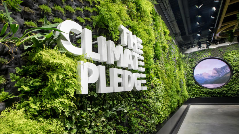 A wall of green plants with white lettering, reading "The Climate Pledge."