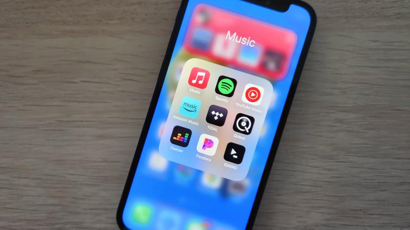 A smartphone lies on a desk, displaying icons for several music streaming apps.