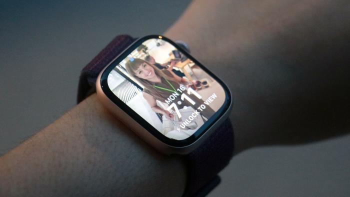 The Apple Watch Series 10 with a Photos watch face open on its home screen, worn on a wrist held in mid-air.